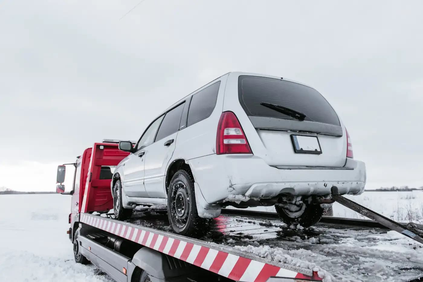 Tow truck carrying a white car in snow