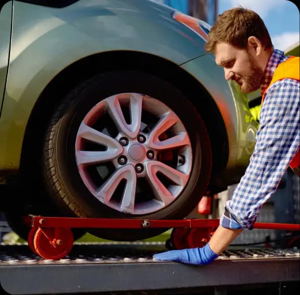 Worker securing a car wheel on a transport bed