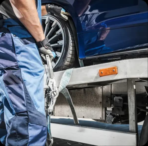 Worker handling chains beside a loaded recovery truck