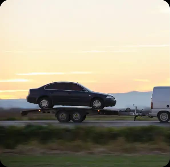 Car transported on a trailer at sunset