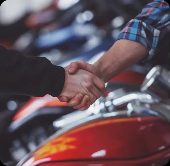Two people shaking hands beside motorcycles