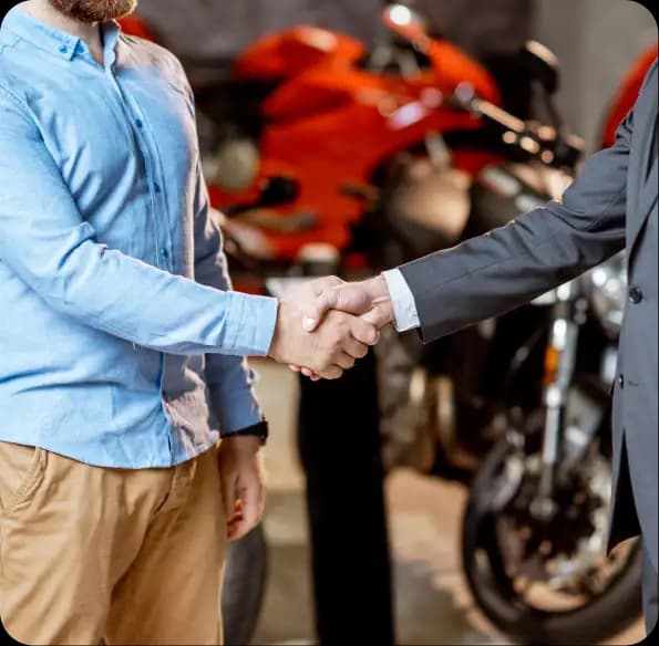 Two people shaking hands beside motorcycles