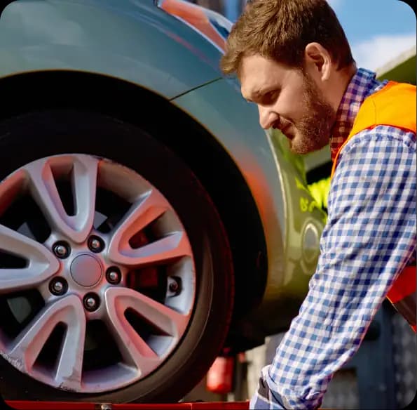 Worker securing a car wheel on a transport bed