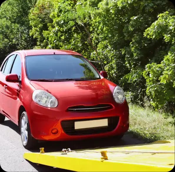 Red car beside a yellow tow truck ramp