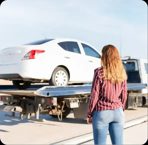 Woman standing beside a car on a tow truck