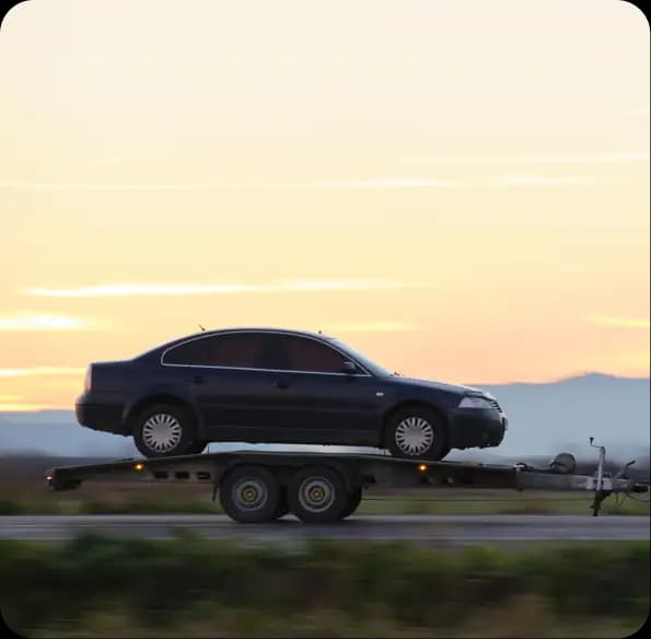 Car transported on a trailer at sunset
