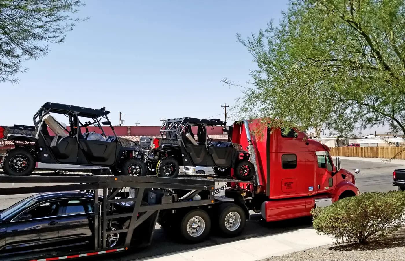 Red car carrier transporting off-road utility vehicles