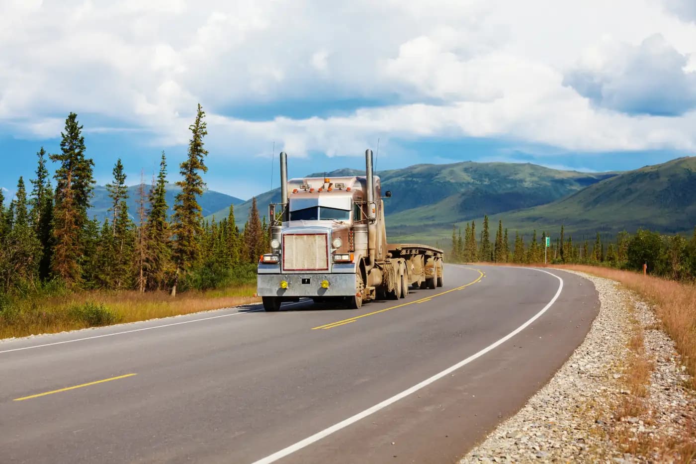 Semi-truck on a curved road through forested mountains