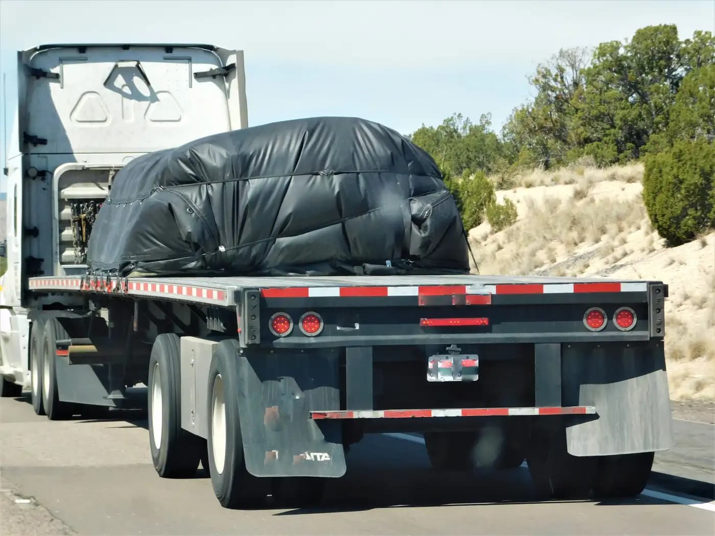 Covered vehicle secured on a flatbed trailer
