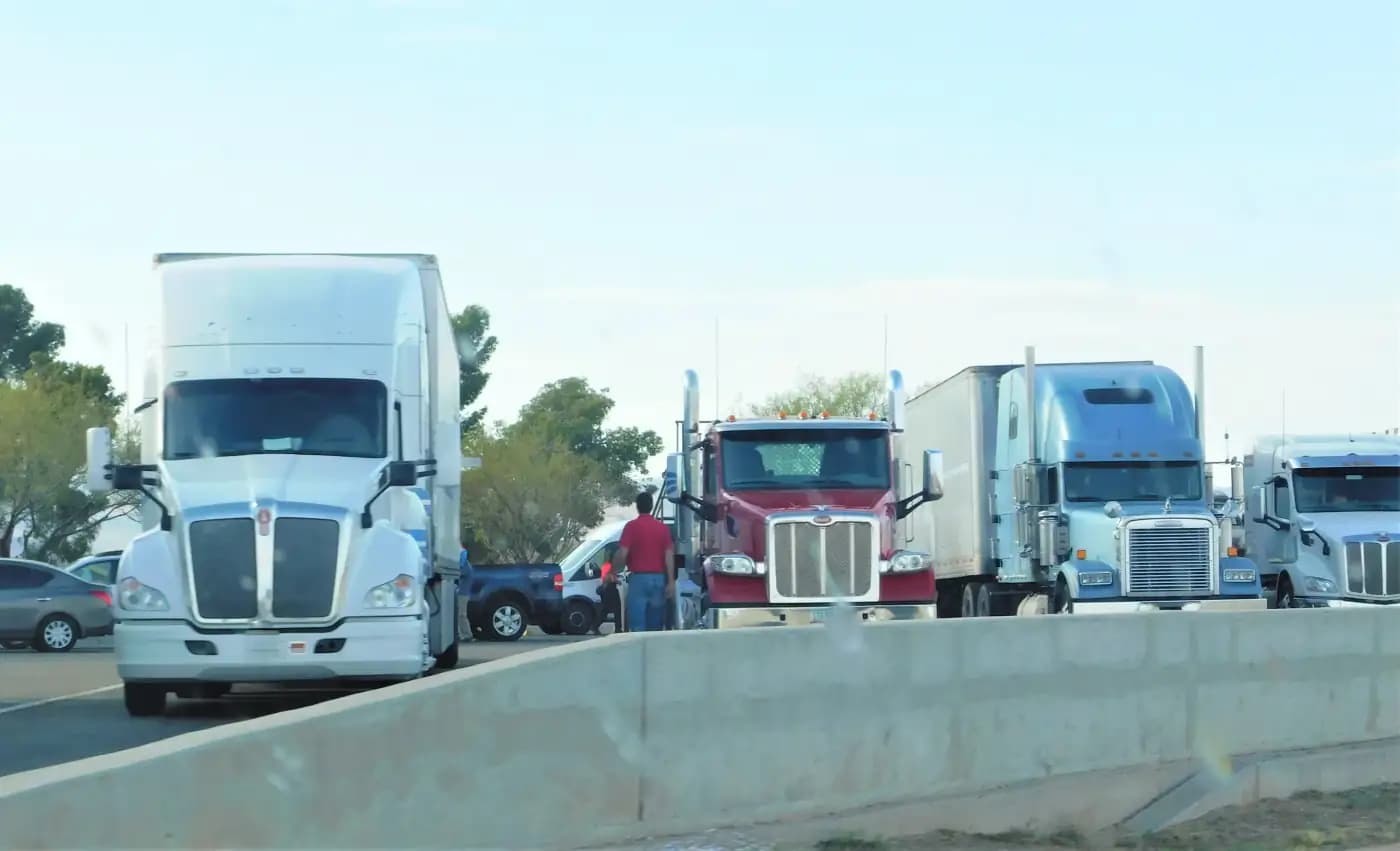 Semi-trucks parked beside a concrete roadside barrier