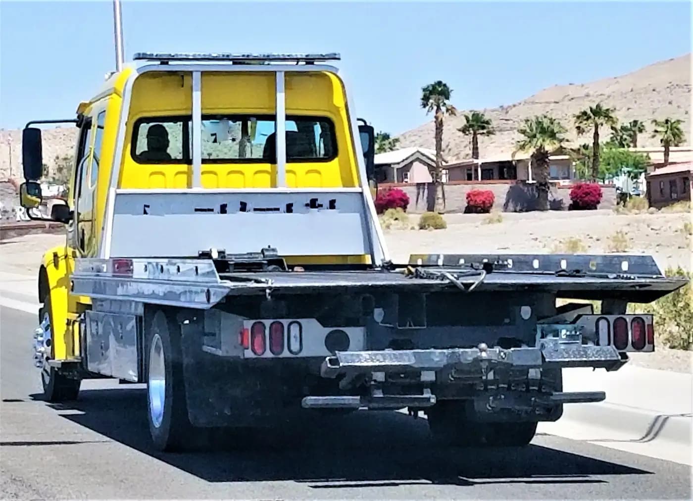Yellow recovery truck with an empty flatbed