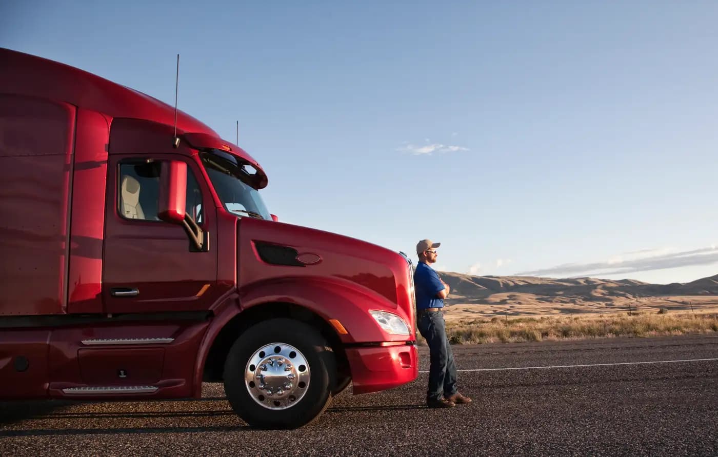 Driver standing in front of a red semi-truck