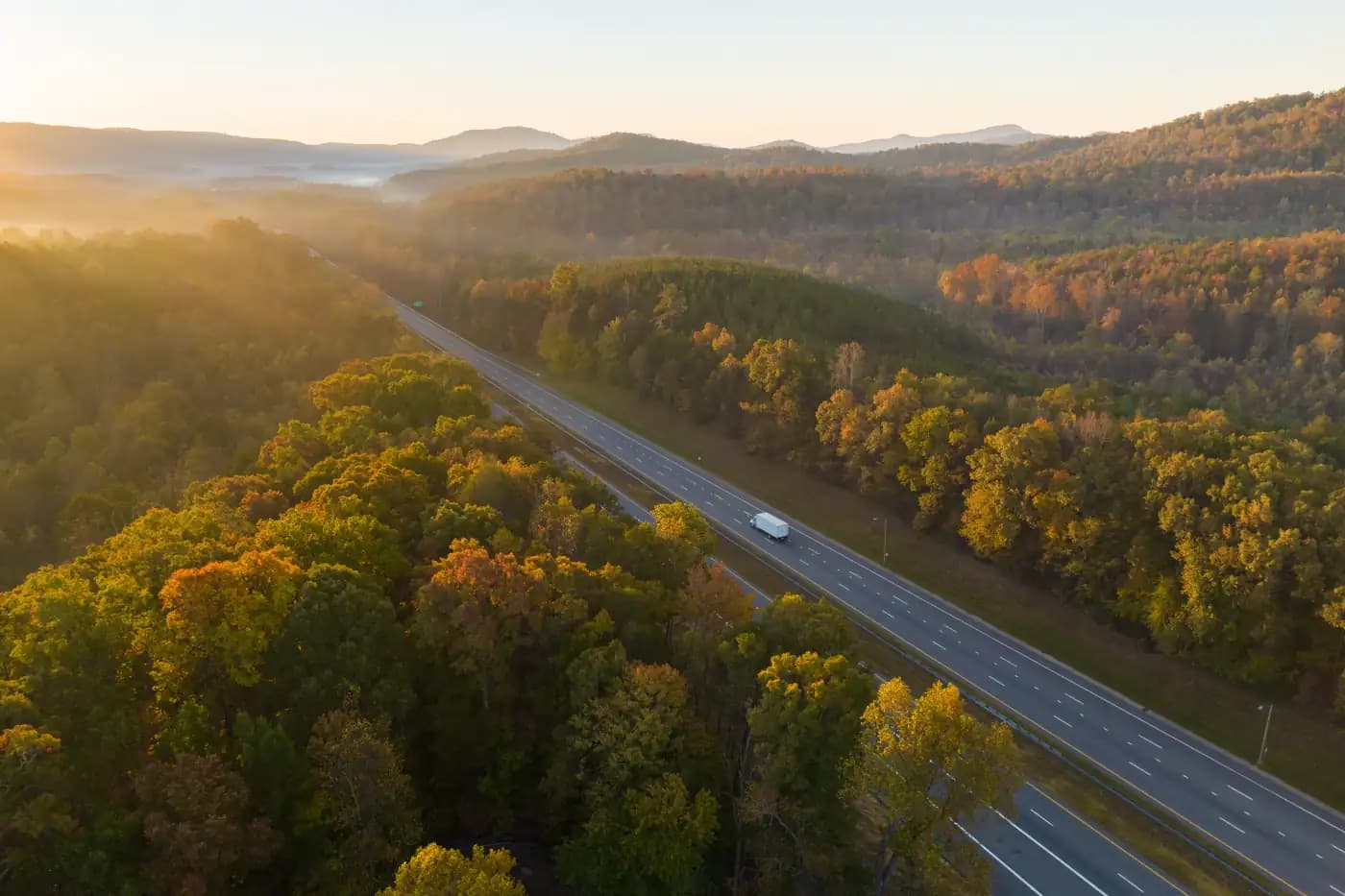 Highway winding through autumn forest at sunset