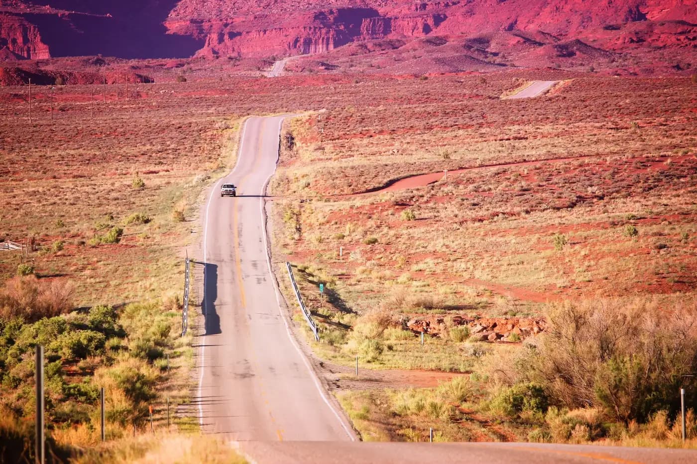 Tractor-trailer on a straight road through red desert cliffs