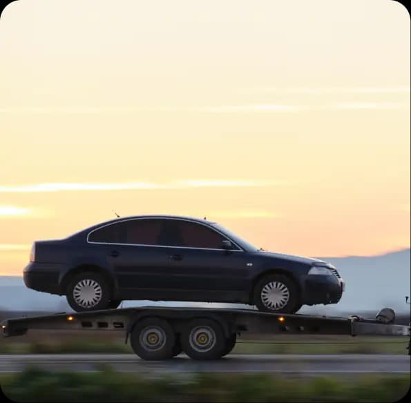 Car transported on a trailer at sunset