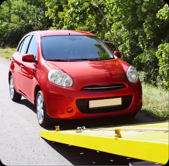 Red car beside a yellow tow truck ramp